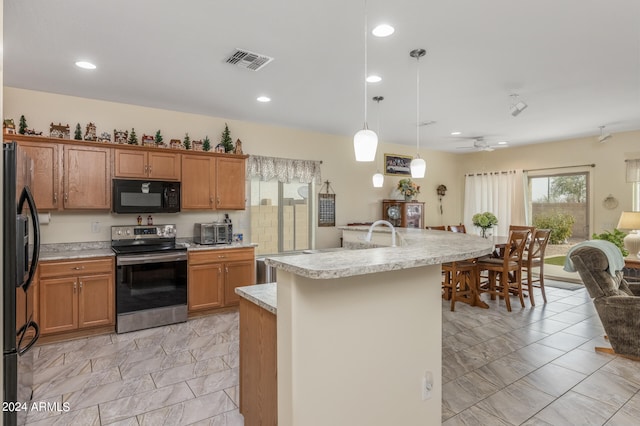 kitchen featuring brown cabinets, light countertops, visible vents, hanging light fixtures, and black appliances