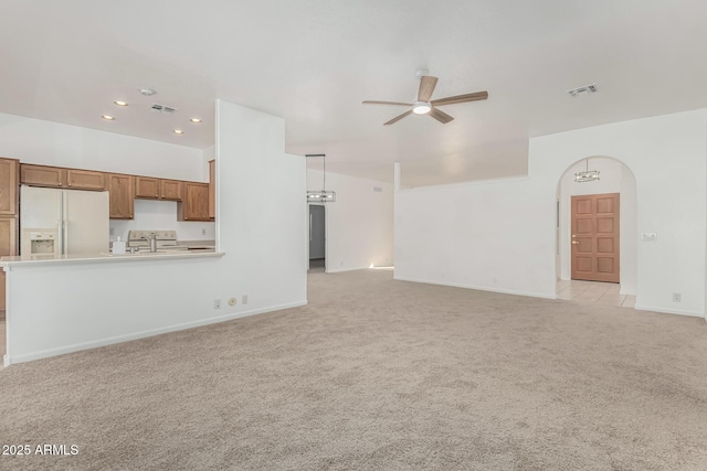 unfurnished living room featuring sink, light colored carpet, and ceiling fan