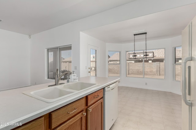 kitchen featuring an inviting chandelier, sink, pendant lighting, and white appliances