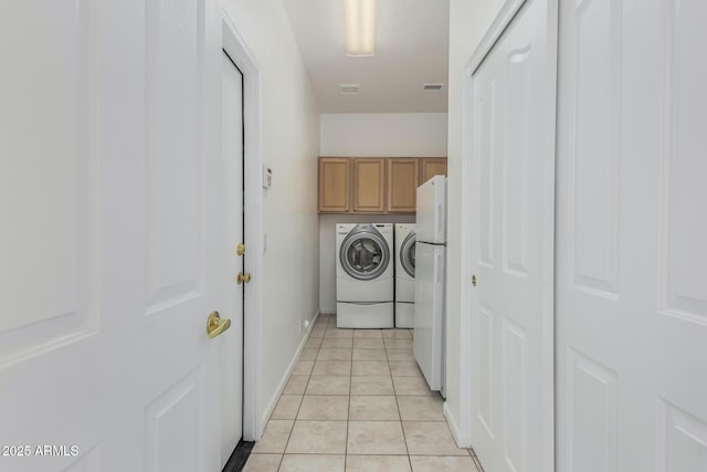 laundry area featuring cabinets, washing machine and dryer, and light tile patterned floors