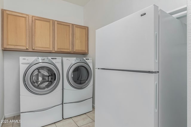 clothes washing area featuring cabinets, washing machine and clothes dryer, and light tile patterned flooring