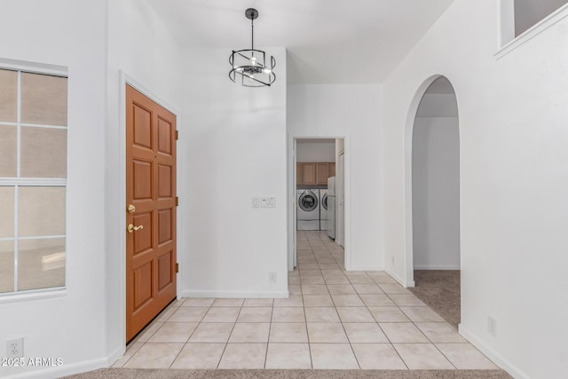 carpeted foyer entrance featuring independent washer and dryer and a notable chandelier