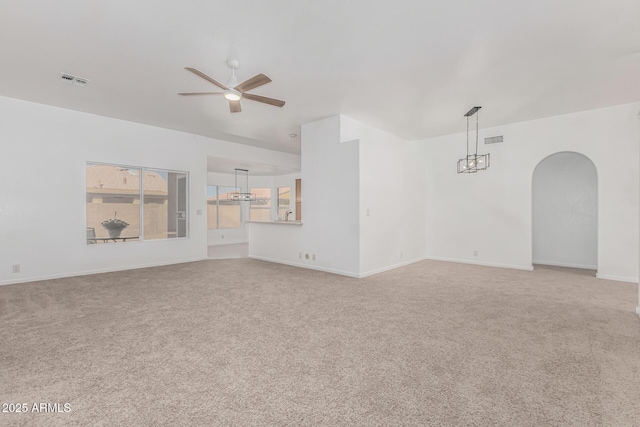 empty room featuring light carpet and ceiling fan with notable chandelier