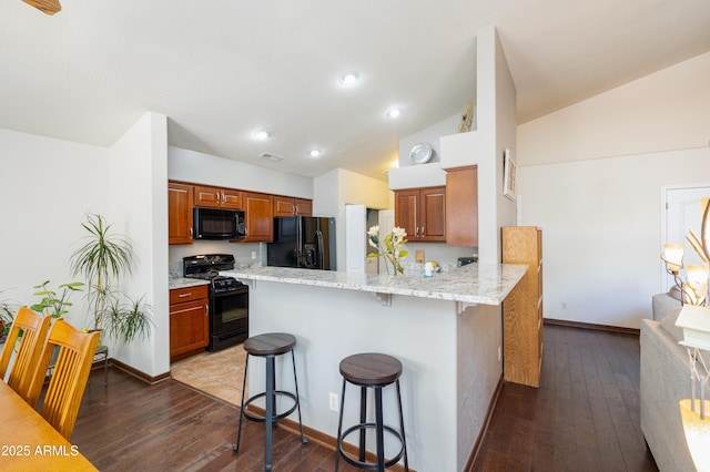 630 W Cattle Drive Trl, Flagstaff, AZ 86005 - kitchen with a kitchen bar, a peninsula, visible vents, black appliances, and lofted ceiling