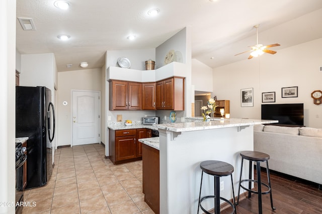 630 W Cattle Drive Trl, Flagstaff, AZ 86005 - kitchen with visible vents, open floor plan, a kitchen breakfast bar, a peninsula, and black appliances