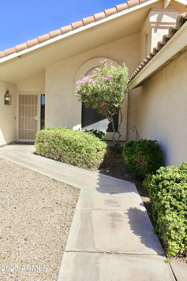 entrance to property with a tiled roof and stucco siding