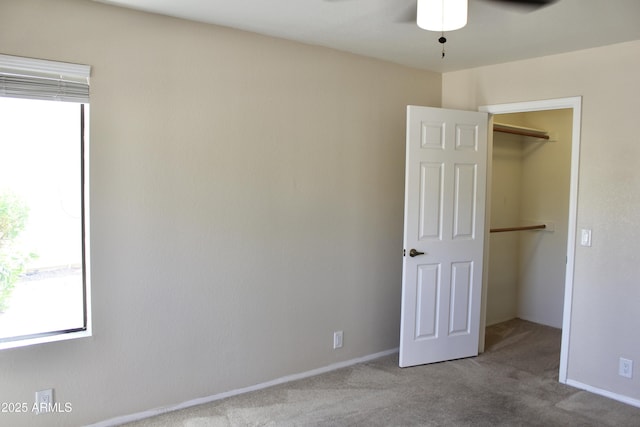 unfurnished bedroom with a closet, baseboards, a walk in closet, and carpet flooring