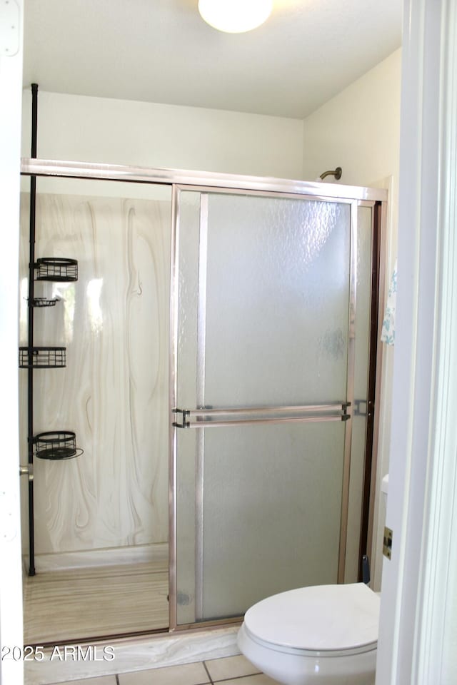 bathroom featuring toilet, a stall shower, and tile patterned floors