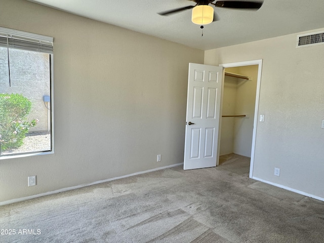 unfurnished bedroom featuring carpet, a spacious closet, visible vents, and multiple windows