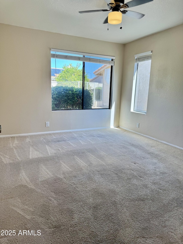 carpeted empty room with ceiling fan and baseboards