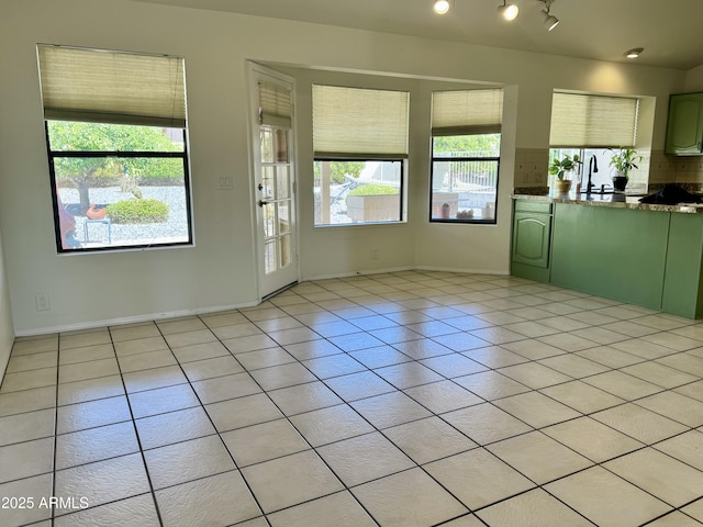 interior space featuring light tile patterned floors, a sink, rail lighting, and baseboards