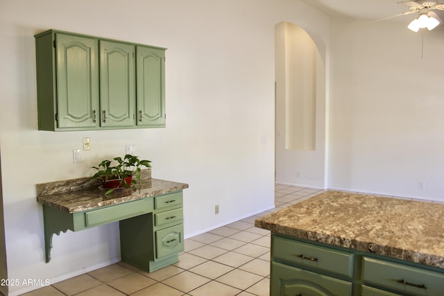 kitchen featuring light tile patterned floors, baseboards, arched walkways, ceiling fan, and green cabinetry