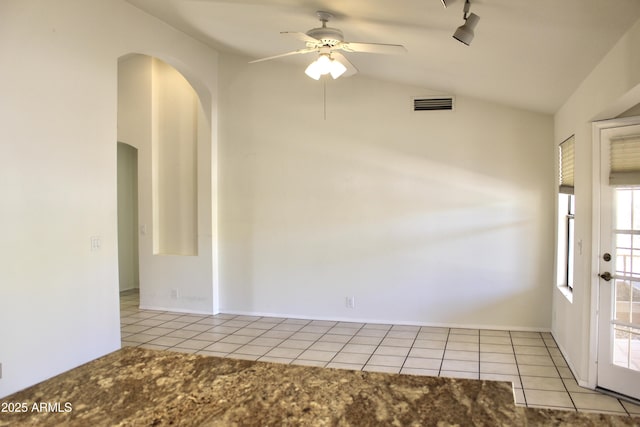 tiled spare room with arched walkways, visible vents, rail lighting, a ceiling fan, and vaulted ceiling