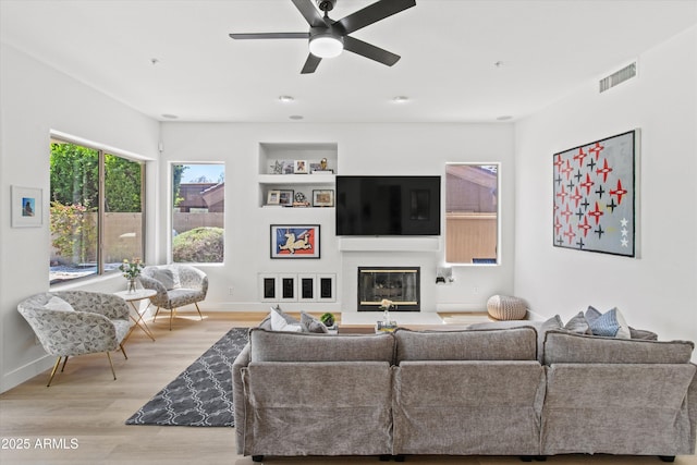 10415 E Rosemary Ln, Scottsdale, AZ 85255 - living area with wood finished floors, a ceiling fan, baseboards, and a glass covered fireplace