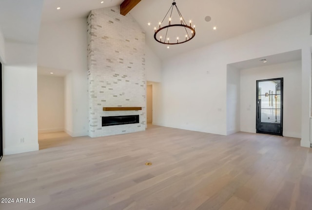 unfurnished living room featuring a large fireplace, high vaulted ceiling, beamed ceiling, and light wood-style floors