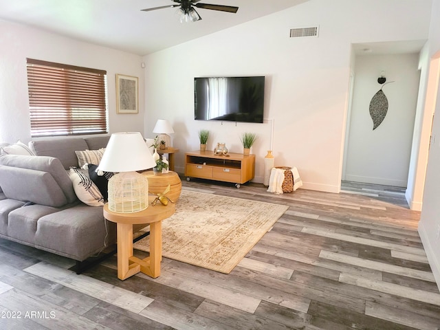 living room with a ceiling fan, visible vents, vaulted ceiling, and wood finished floors