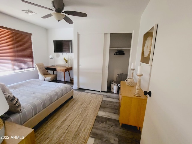 bedroom with a closet, wood finished floors, visible vents, and a ceiling fan