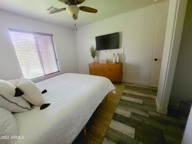 bedroom featuring visible vents, ceiling fan, baseboards, and wood finished floors