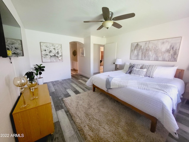 bedroom featuring a ceiling fan, arched walkways, and wood finished floors