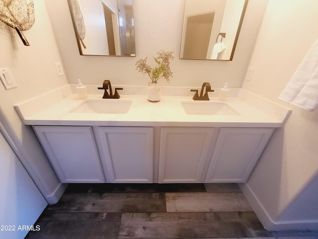 full bathroom featuring double vanity, wood finished floors, and a sink