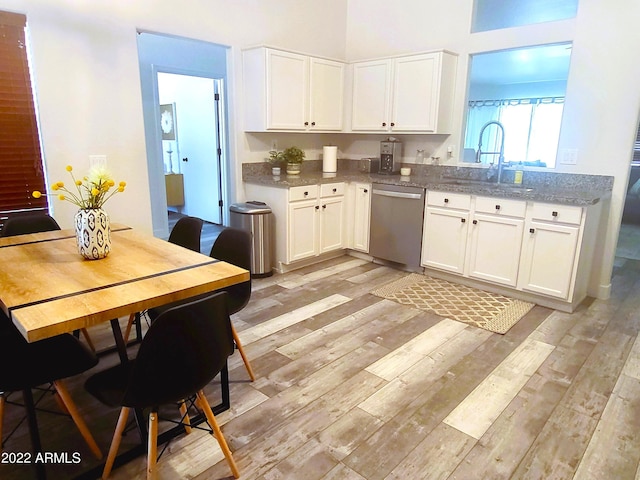 kitchen with dishwasher, light wood-type flooring, a sink, and white cabinets