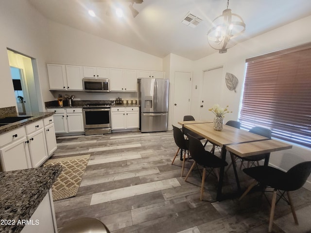 kitchen featuring lofted ceiling, stainless steel appliances, visible vents, and light wood-style floors