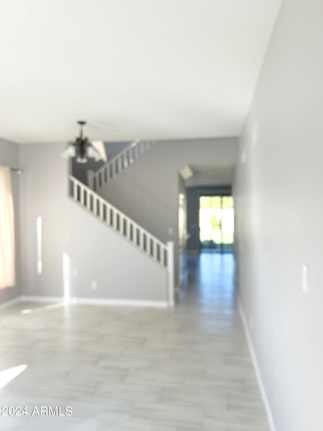 stairway with hardwood / wood-style flooring and a chandelier