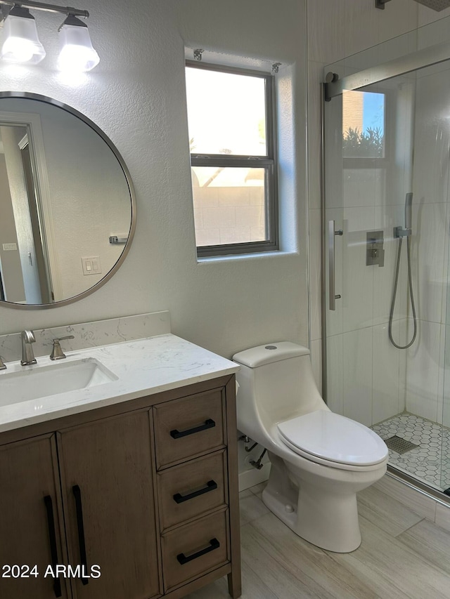 bathroom featuring toilet, a shower with shower door, and vanity