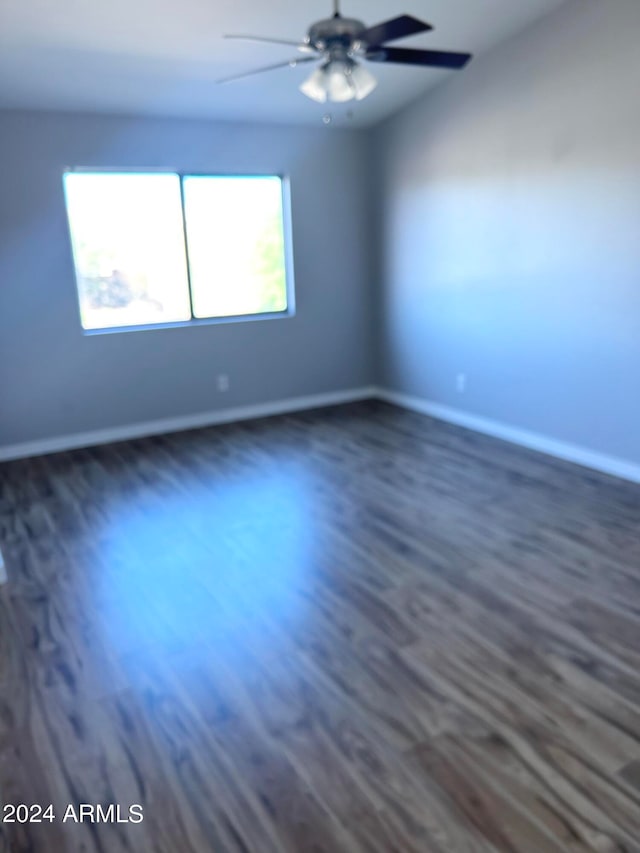 unfurnished room featuring dark wood-type flooring and ceiling fan