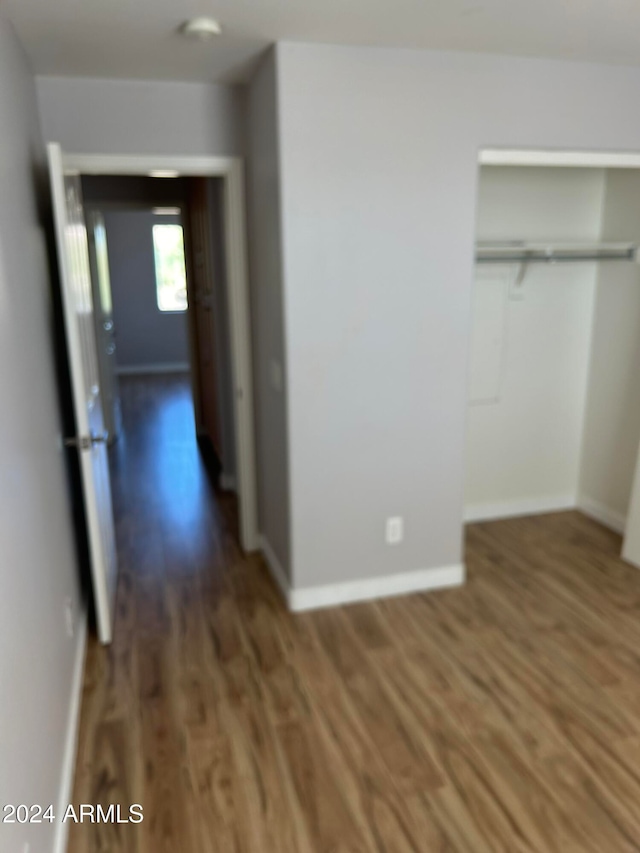 unfurnished bedroom with a closet and dark hardwood / wood-style flooring