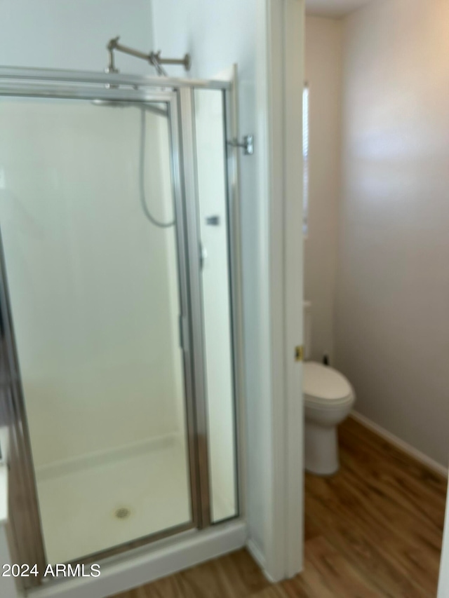 bathroom featuring a shower with door, hardwood / wood-style floors, and toilet