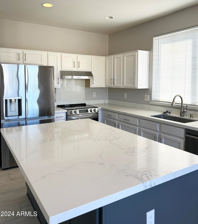 kitchen with white cabinetry, appliances with stainless steel finishes, sink, and a kitchen island