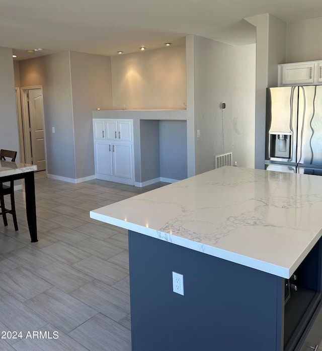 kitchen featuring a center island, white cabinets, and stainless steel refrigerator with ice dispenser