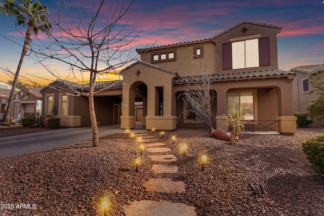 mediterranean / spanish-style home with a porch, a tile roof, driveway, and stucco siding