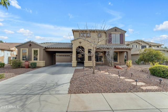 mediterranean / spanish home with a garage, driveway, a tile roof, and stucco siding