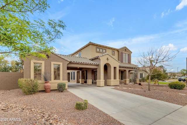 mediterranean / spanish home featuring driveway, a tile roof, fence, and stucco siding