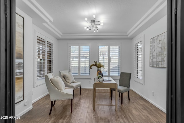 interior space featuring a raised ceiling, a notable chandelier, baseboards, and wood finished floors