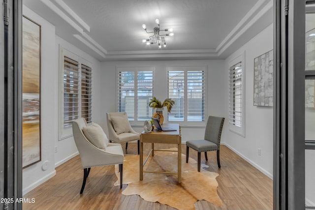 living area with light wood-style floors, a tray ceiling, a notable chandelier, and baseboards