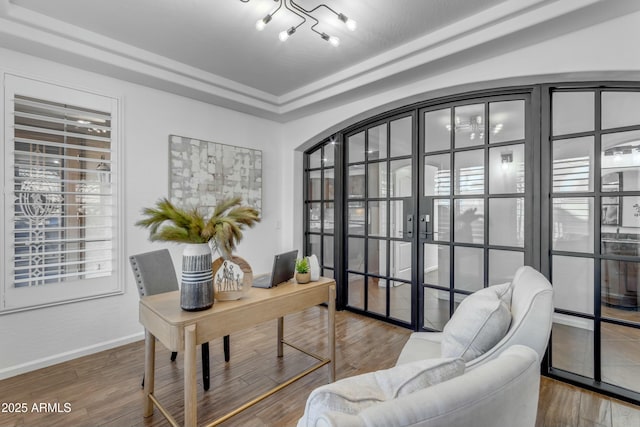 home office with a raised ceiling, baseboards, and wood finished floors