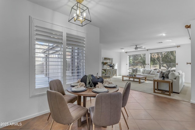 dining space featuring ceiling fan with notable chandelier, tile patterned flooring, visible vents, and baseboards