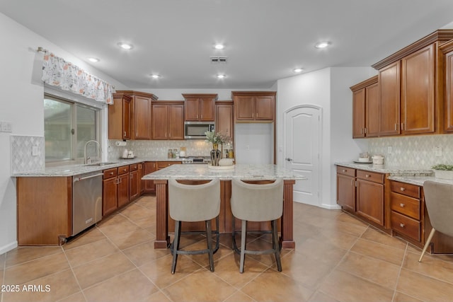 kitchen with stainless steel appliances, brown cabinetry, visible vents, and a sink