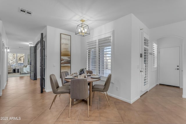 dining space with a chandelier, light tile patterned flooring, visible vents, and baseboards