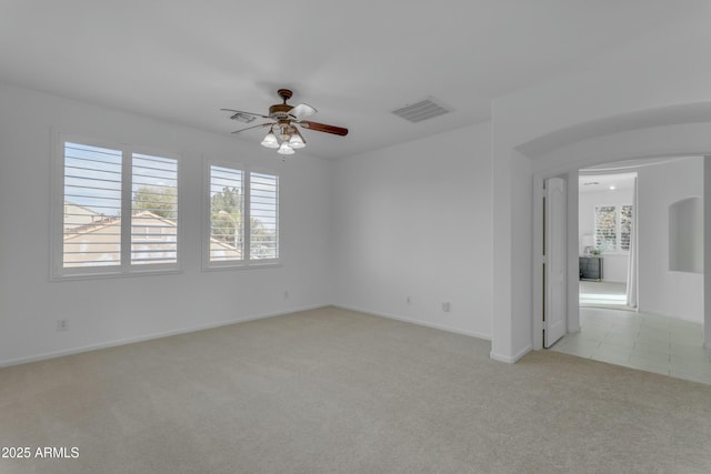 spare room featuring light carpet, baseboards, visible vents, and a ceiling fan