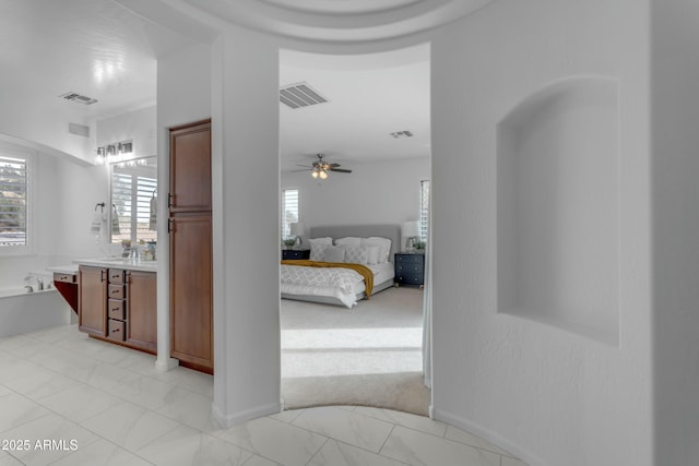 hallway featuring marble finish floor, a sink, and visible vents