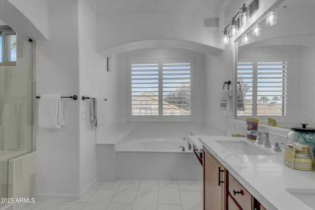 full bathroom featuring double vanity, a garden tub, plenty of natural light, and a sink