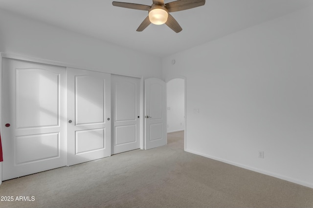 unfurnished bedroom featuring a closet, carpet, a ceiling fan, and baseboards