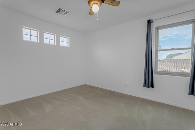 empty room with baseboards, visible vents, a ceiling fan, and light colored carpet