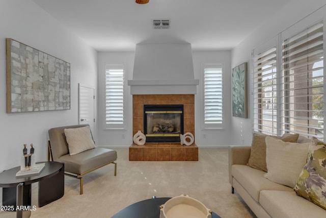 carpeted living area with a tile fireplace, visible vents, and a healthy amount of sunlight