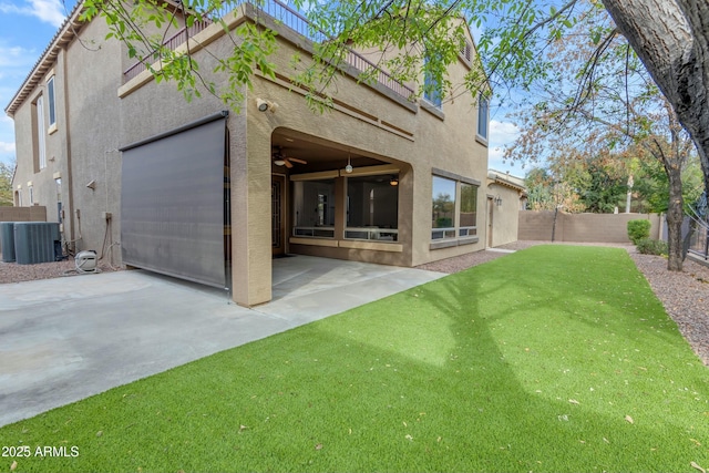 back of house with a patio, central AC unit, a fenced backyard, a yard, and stucco siding