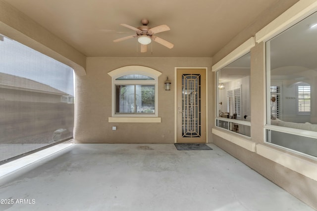 entrance to property featuring a ceiling fan, a patio area, and stucco siding